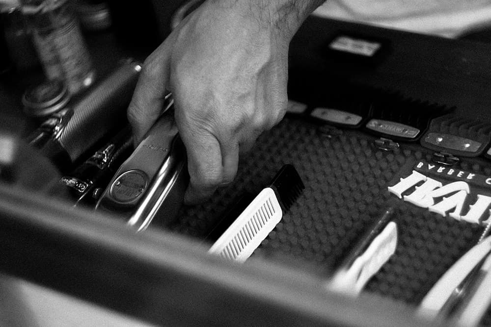 Mano junto a herramientas de barbería en una fotografía editorial en blanco y negro